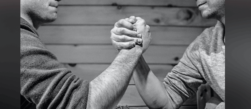 Capture One vs Lightroom: Which Photo Editing Software Reigns Supreme? Two men arm wrestling