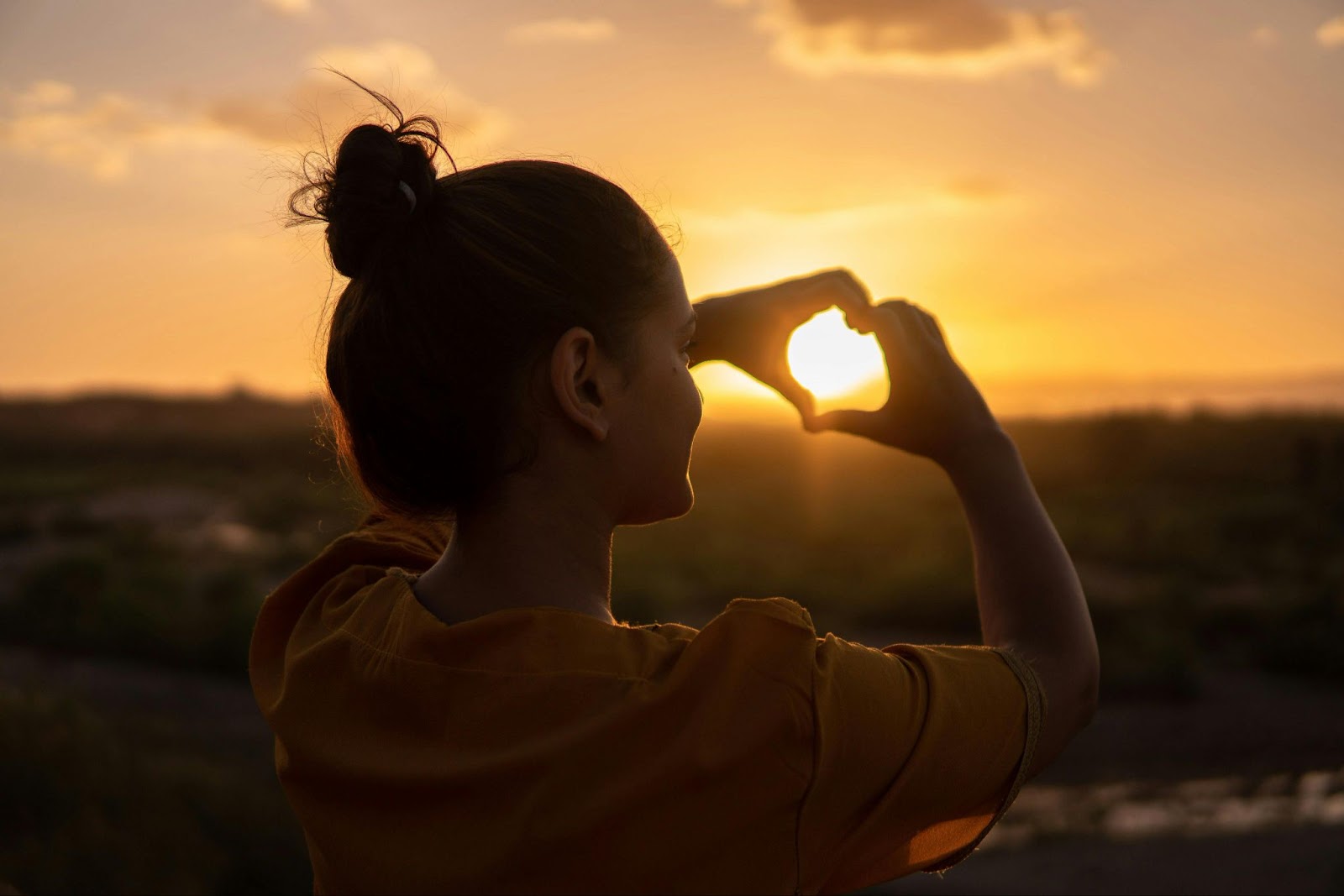 11 Golden Hour Photography Tips For Your Next Photoshoot golden hour photography woman making heart sign with hands